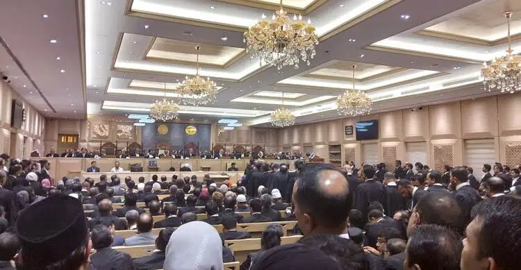 প্রধান বিচারপতির বিদায়ী সংবর্ধনা বাংলাদেশের প্রধান বিচারপতি ড. সৈয়দ রেফাত আহমেদের বিদায়ী সংবর্ধনা শুরু হয়েছে। বৃহস্পতিবার (১৮ ডিসেম্বর) সকাল সাড়ে ১০টায় বাংলাদেশ সুপ্রিম কোর্টের আপিল বিভাগের ১নং কোর্টে (প্রধান বিচারপতির এজলাস) এই সংবর্ধনা অনুষ্ঠান শুরু হয়। এ সময় সর্বোচ্চ আদালতের আপিল বিভাগ কানায় কানায় পূর্ণ হয়ে যায়। এদিন সুপ্রিম কোর্ট আইনজীবী সমিতি (বার অ্যাসোসিয়েশন) ও অ্যাটর্নি জেনারেল কার্যালয়ের পক্ষ থেকে প্রধান বিচারপতি সৈয়দ রেফাত আহমেদের বিদায়ী সংবর্ধনার আয়োজন করে। সুপ্রিম কোর্টের গণসংযোগ কর্মকর্তা মো. শফিকুল ইসলামের দেওয়া বিজ্ঞপ্তিতে জানানো হয়, সুপ্রিম কোর্ট আইনজীবী সমিতির পক্ষে সভাপতি এ এম মাহবুব উদ্দিন খোকন ও অ্যাটর্নি জেনারেল কার্যালয়ের পক্ষে অ্যাটর্নি জেনারেল মো. আসাদুজ্জামান দেশের প্রধান বিচারপতিকে বিদায়ী সংবর্ধনা দিচ্ছেন। তারই ধারাবাহিকতায় আজ অনুষ্ঠান চলছে। ২০২৪ সালের জুলাই-আগস্টে ছাত্র-জনতার গণঅভ্যুত্থানের প্রেক্ষাপটে দেশের ২৫তম প্রধান বিচারপতির দায়িত্ব নেন ড. সৈয়দ রেফাত আহমেদ। ২০২৪ সালের ১১ আগস্ট প্রধান বিচারপতি হিসেবে তিনি শপথ নেন। সংবিধান অনুযায়ী, বিচারপতিদের অবসরের বয়স ৬৭ বছর। প্রধান বিচারপতি সৈয়দ রেফাত আহমেদ ১৯৫৮ সালের ২৮ ডিসেম্বর জন্মগ্রহণ করেন। সে হিসেবে প্রধান বিচারপতির বয়স ৬৭ বছর পূর্ণ হতে যাচ্ছে ২৭ ডিসেম্বর। সেদিন ছুটি থাকায় আগামীকাল তার শেষ কর্মদিবস। প্রথা অনুসারে শেষ কর্মদিবসে বিদায়ী বিচারপতিকে সুপ্রিম কোর্ট আইনজীবী সমিতি ও অ্যাটর্নি জেনারেল কার্যালয়ের পক্ষ থেকে বিদায়ী সংবর্ধনা জানানো হয়। প্রধান বিচারপতির বিদায়ী সংবর্ধনা, কানায় কানায় পূর্ণ আপিল বিভাগ এর আগে দেশের জেলা আদালতগুলোতে কর্মরত উচ্চ পর্যায়ের বিচার বিভাগীয় কর্মকর্তাদের উদ্দেশে গত রোববার (১৪ ডিসেম্বর) প্রধান বিচারপতি হিসেবে নিজের বিদায়ী অভিভাষণে বিচারপতি সৈয়দ রেফাত আহমেদ কথা বলেন। সুপ্রিম কোর্ট মিলনায়তনে এ উপলক্ষে গুরুত্বপূর্ণ অধিবেশনের আয়োজন করা হয়। প্রধান বিচারপতি সৈয়দ রেফাত আহমেদ ঢাকা বিশ্ববিদ্যালয়ের সাবেক ছাত্র। তিনি বিশ্বখ্যাত অক্সফোর্ড বিশ্ববিদ্যালয়ের ওয়াডাম কলেজ থেকে প্রথম শ্রেণিতে আইন শাস্ত্রের ওপর ডিগ্রি অর্জন করেন। পরে মাস্টার্স ও পিএইচডি করেন যুক্তরাষ্ট্রের টাফ্টস ইউনিভার্সিটির ফ্লেচার স্কুল অব ল’ অ্যান্ড ডিপ্লোমেসিতে। সৈয়দ রেফাত আহমেদ অভিবাসন আইন বিশেষজ্ঞ হিসেবে ইউএনএইচসিআরের সঙ্গে কাজ করেন। সৈয়দ রেফাত আহমেদ ১৯৮৪ সালে ঢাকা জেলা আদালতে এবং ১৯৮৬ সালে হাইকোর্ট বিভাগের আইনজীবী হন। ২০০৩ সালের ২৭ এপ্রিল তিনি হাইকোর্টের অতিরিক্ত বিচারক হন। এর দুই বছর পর তিনি হাইকোর্টের স্থায়ী বিচারপতি হন। ছবি : সংগৃহীত